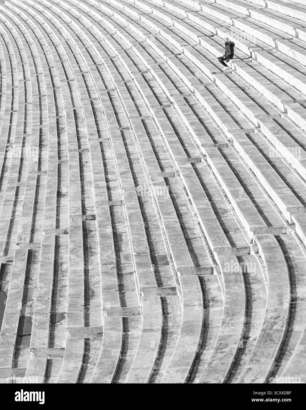 Einsamer Mann sitzt auf Marmorstufen im Panathenaic-Stadion in Athen, Griechenland. Stockfoto