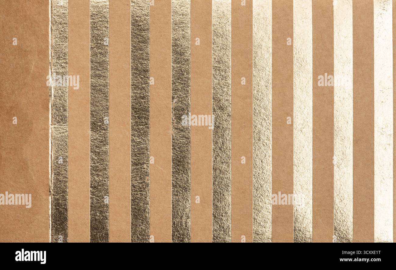 Eine Reihe glänzender Metallfolienstreifen verläuft vertikal über eine strukturierte braune Oberfläche und schafft ein auffälliges Design, das sich perfekt für künstlerische Projekte eignet Stockfoto