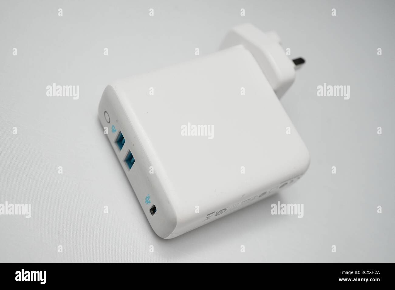 London, Großbritannien – 2025.10.16 – Nahaufnahme eines weißen USB-Ladegeräts mit zwei blauen USB-Anschlüssen und einem UK-Steckerdesign, platziert auf einem sauberen weiß Stockfoto