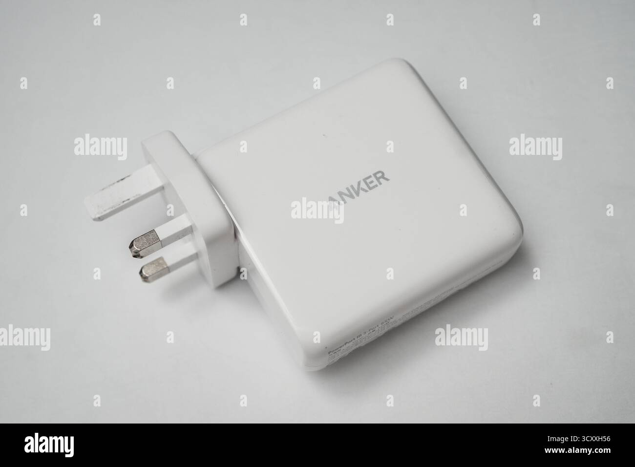 London, Großbritannien – 2025.10.16 – Nahaufnahme eines weißen USB-Ladegeräts mit zwei blauen USB-Anschlüssen und einem UK-Steckerdesign, platziert auf einem sauberen weiß Stockfoto