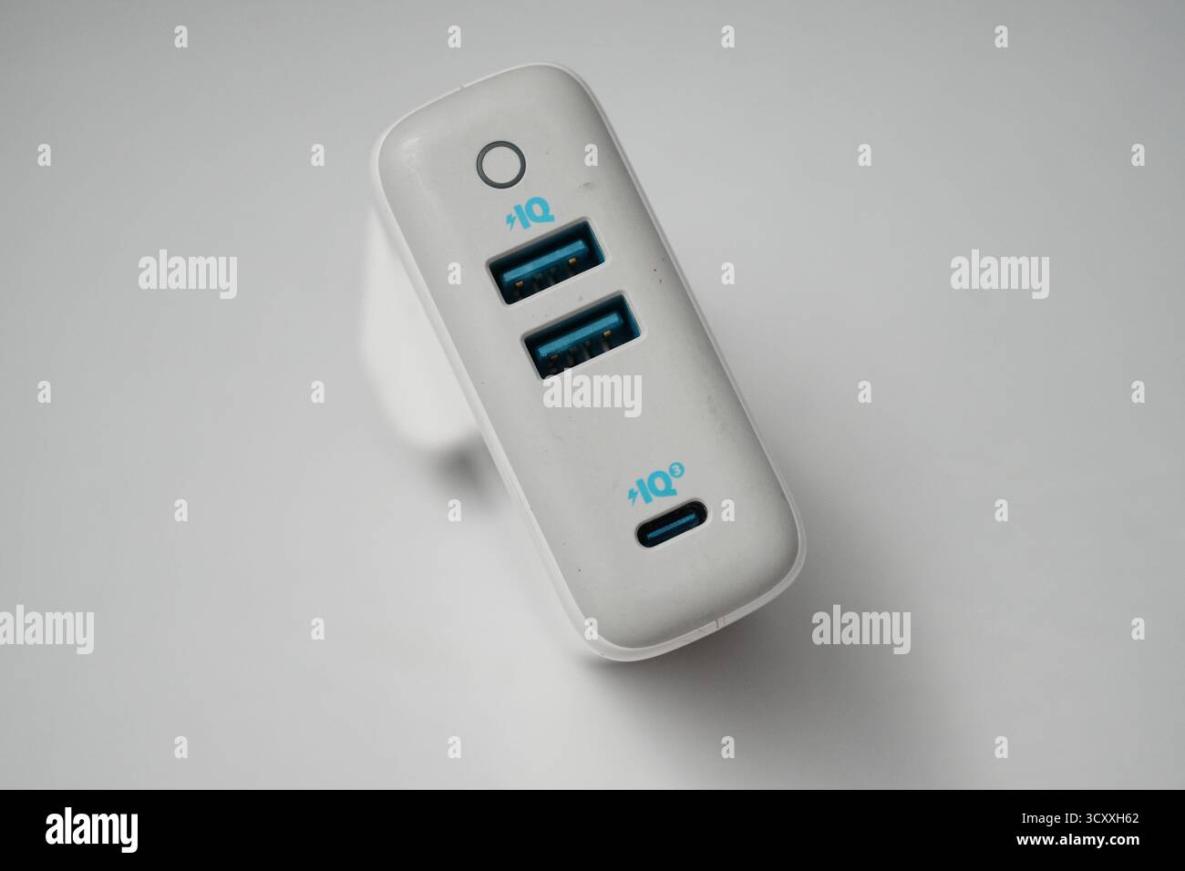London, Großbritannien – 2025.10.16 – Nahaufnahme eines weißen USB-Ladegeräts mit zwei blauen USB-Anschlüssen und einem UK-Steckerdesign, platziert auf einem sauberen weiß Stockfoto