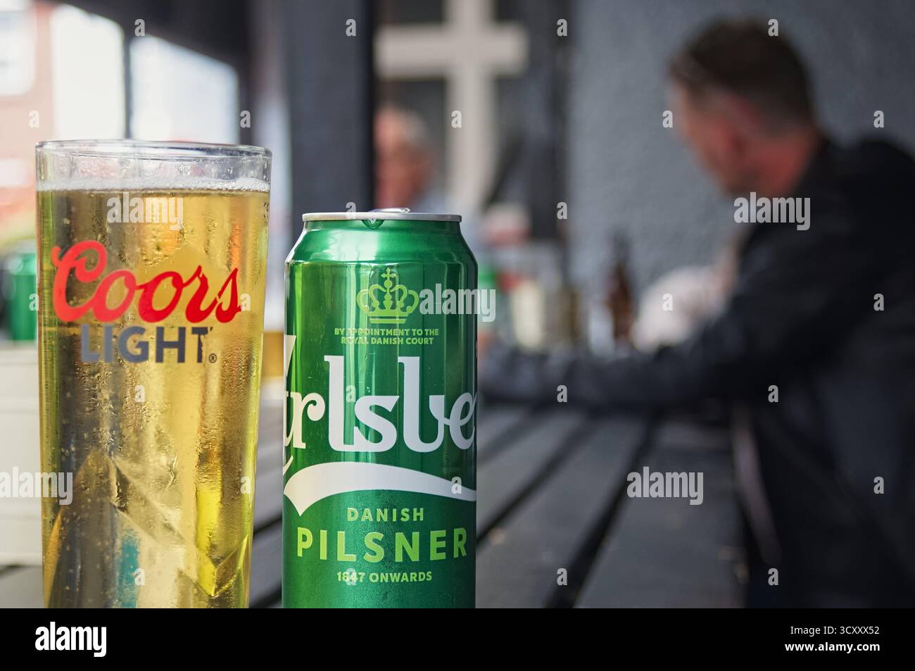 Ein Glas Lagerbier und eine Carlsberg-Dose auf einem Pub-Tisch Stockfoto