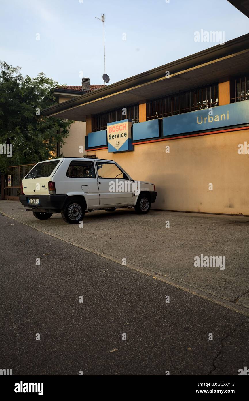 Mantova, Italien - 7. SEPTEMBER 2025 - Fiat Panda parkt in einem kleinen Bereich vor einem Autohaus mit Werbetafeln an der Fassade, die in der Sonne zu sehen sind Stockfoto