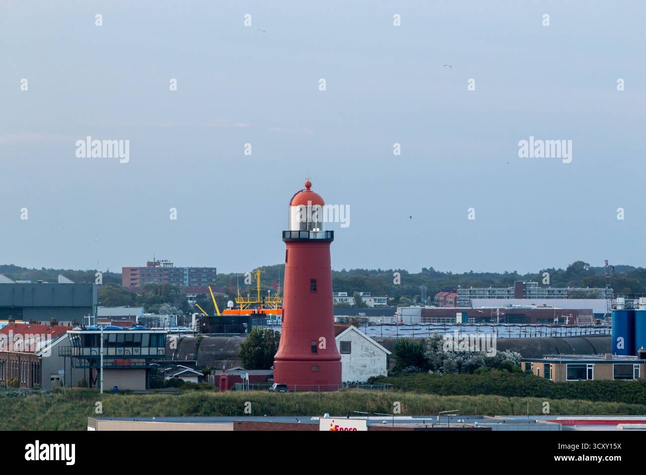 Amsterdam, Niederlande - 5. August 2025: Der Leuchtturm überblickt eine Küstenstadt mit Booten und Gebäuden. Stockfoto