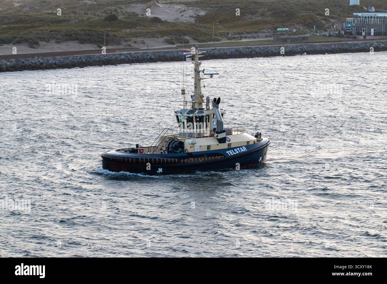 Amsterdam, Niederlande - 5. August 2025: Ein Schlepper fährt sanft über das Wasser mit klarem Himmel dahinter. Stockfoto