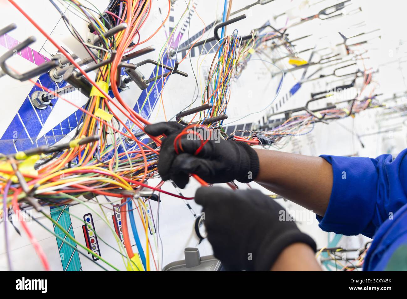 Fabrik für elektrische Kabelbäume Kfz-, Verkabelungs- und Steckverbinder Kabelbaum afroamerikanischer Arbeiter Verdrahtung einer Tafelvorlage Stockfoto