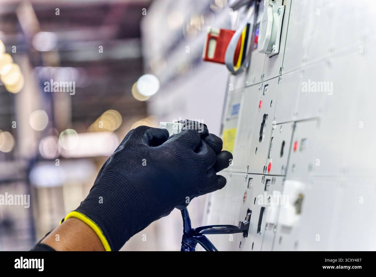 afroamerikanischer Arbeiter in einer Elektrofabrik für Kabelbäume in der Automobilfabrik, der die Verkabelung und die Steckverbinder auf einer Vorlagenplatte erledigt Stockfoto