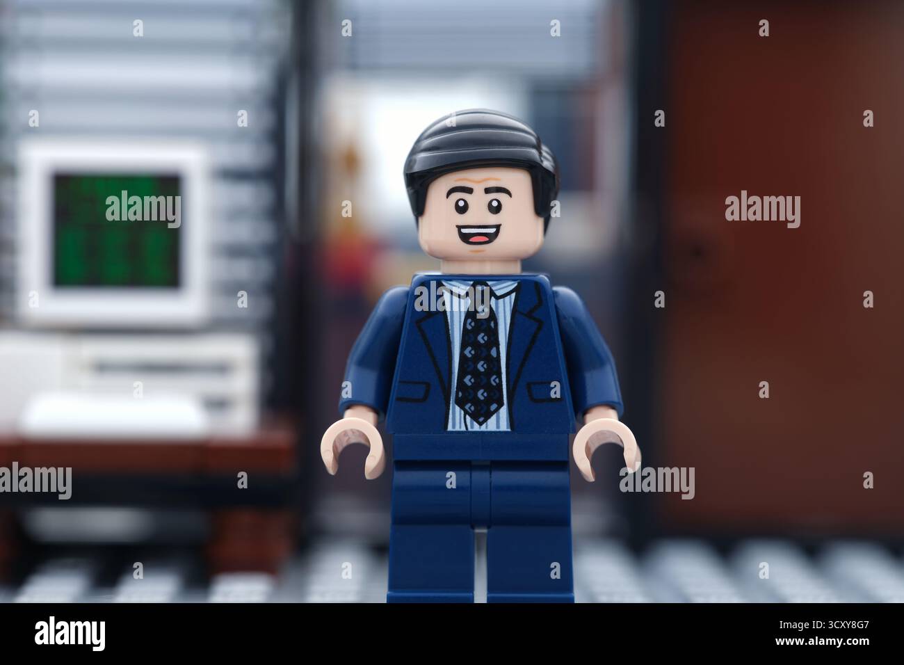 Tambow, Russische Föderation - 16. Oktober 2025 Ein glücklicher Lego-Geschäftsmann, der in seinem Büro vor einem Computer steht. Stockfoto