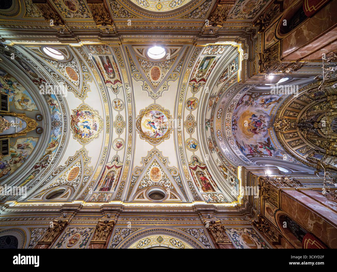 Vergoldete Rahmen und farbenfrohe Fresken zieren die Decke des Basílica de la Macarena und heben das neobaroke Design und die tiefe Hingabe in Sevilla hervor. Stockfoto