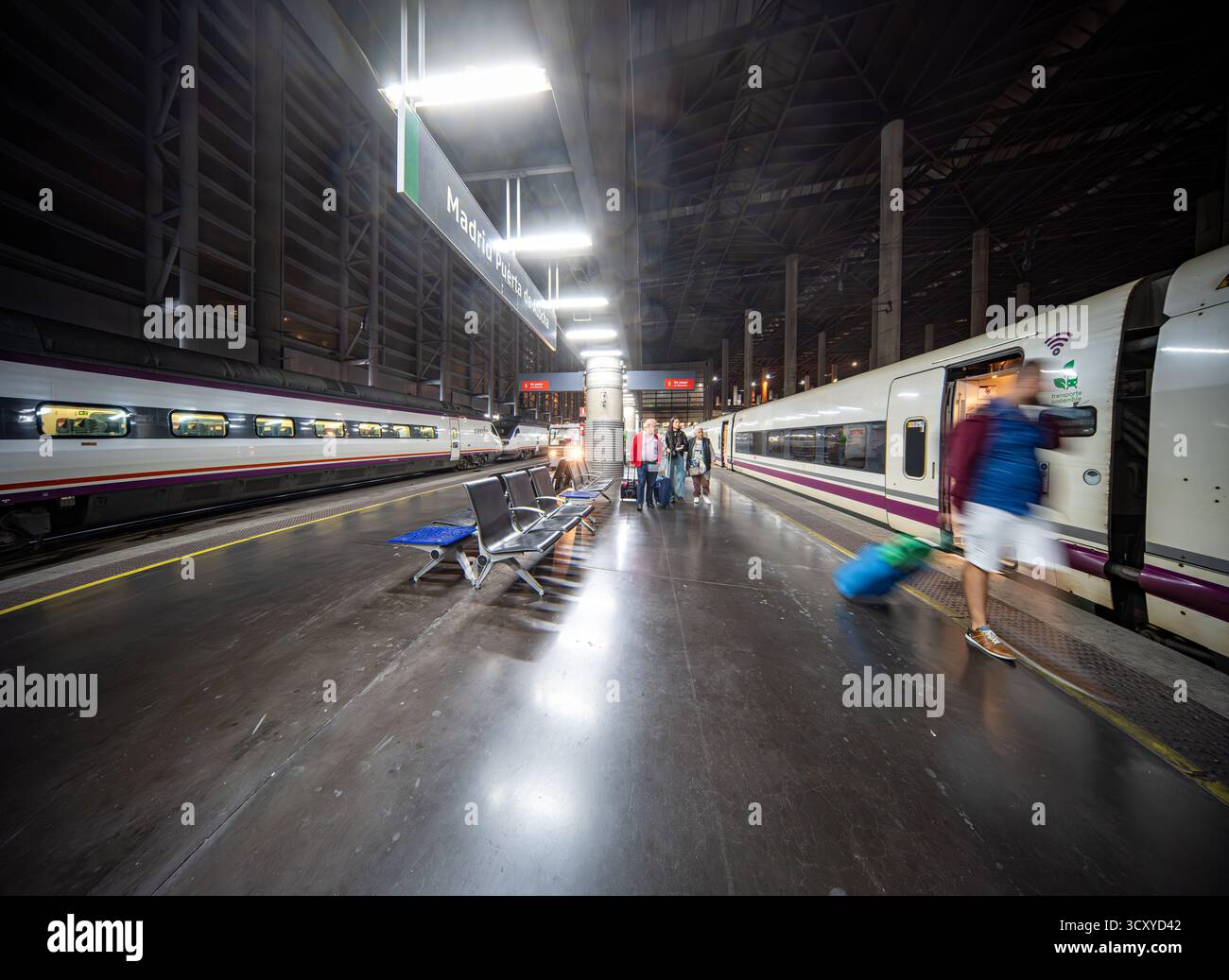 Reisende treffen sich am Bahnhof Atocha in Madrid, während AVE-Züge sich während einer geschäftigen Reisezeit in der geschäftigen Stadt auf die Abfahrt vorbereiten. Stockfoto
