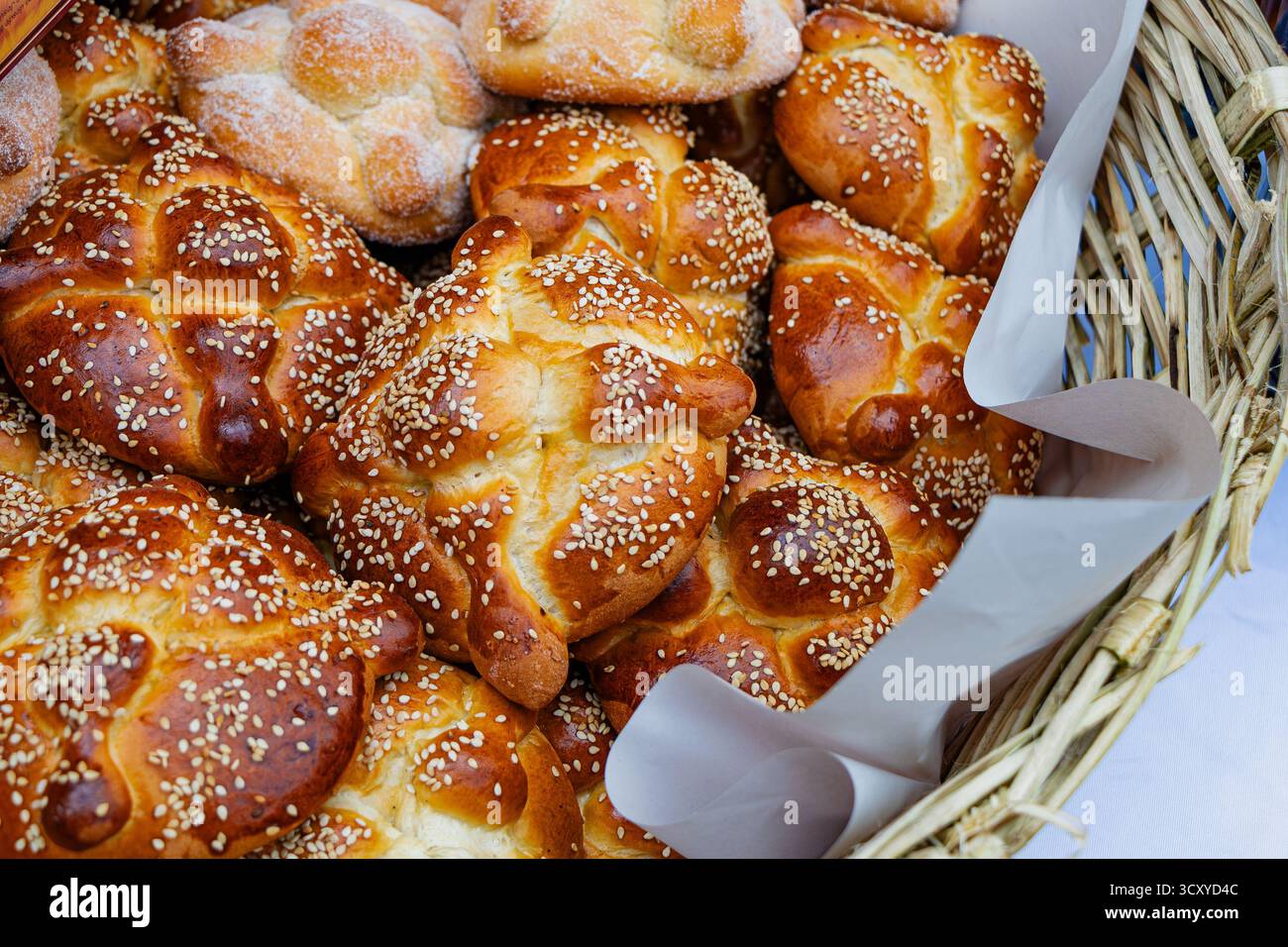 Traditionelles mexikanisches Pan de Muerto (Brot der Toten) mit Sesamsamen, gestapelt in einem rustikalen Korb. Köstliches, kultiges „Day of the Dead“-Essen. Stockfoto