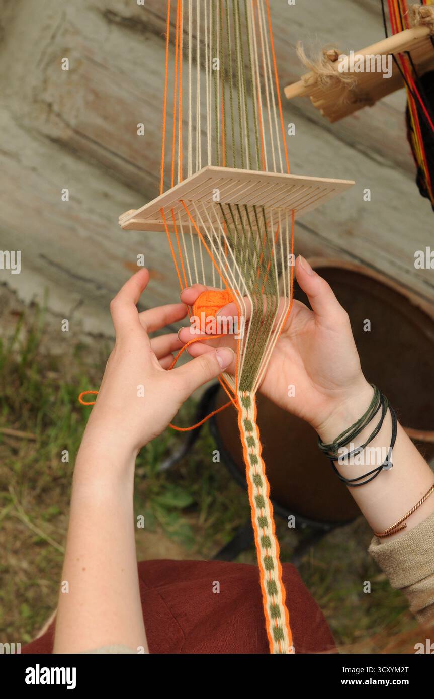 Händeweben eines dekorativen Bandes mit einer traditionellen Technik der Tablettenweben während einer frühmittelalterlichen Handwerkskunst in Trzcinica, Subkarpaten, Stockfoto