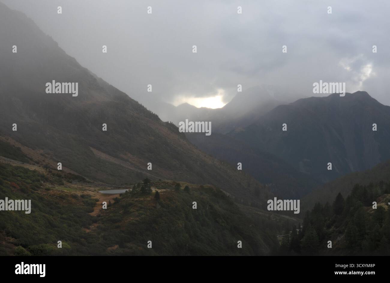 Berglandschaft im Herbst, Herbstfarben, ein Bergsee, trübe Berge in der Ferne und ein grau bewölkter Himmel Stockfoto