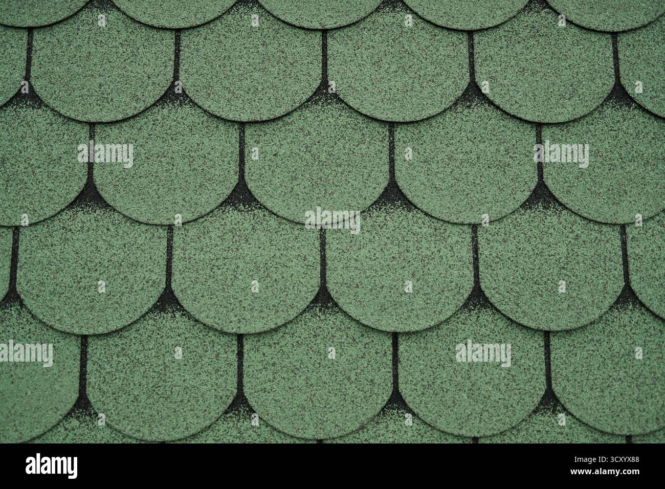 Nahaufnahme von grünen Asphaltdachschindeln, die ein Muster bilden. Ideal für Bau-, Architektur-, Hintergrund- oder Dachkonstruktionsprojekte. Stockfoto