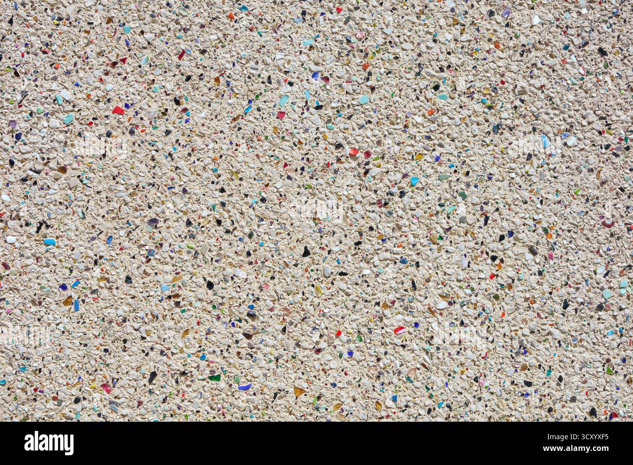 Heller, rauer Putz mit beiliegenden grauen und farbigen Steinen Stockfoto