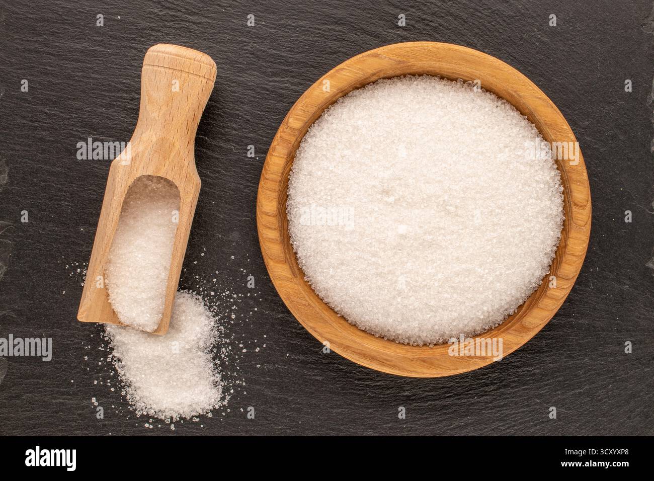 Zucker auf einem Holzteller auf einem Schieferstein, Nahaufnahme, Draufsicht. Stockfoto