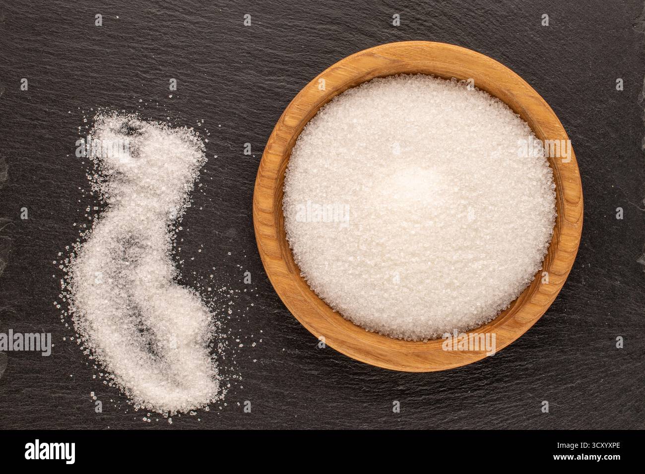 Zucker auf einem Holzteller auf einem Schieferstein, Nahaufnahme, Draufsicht. Stockfoto