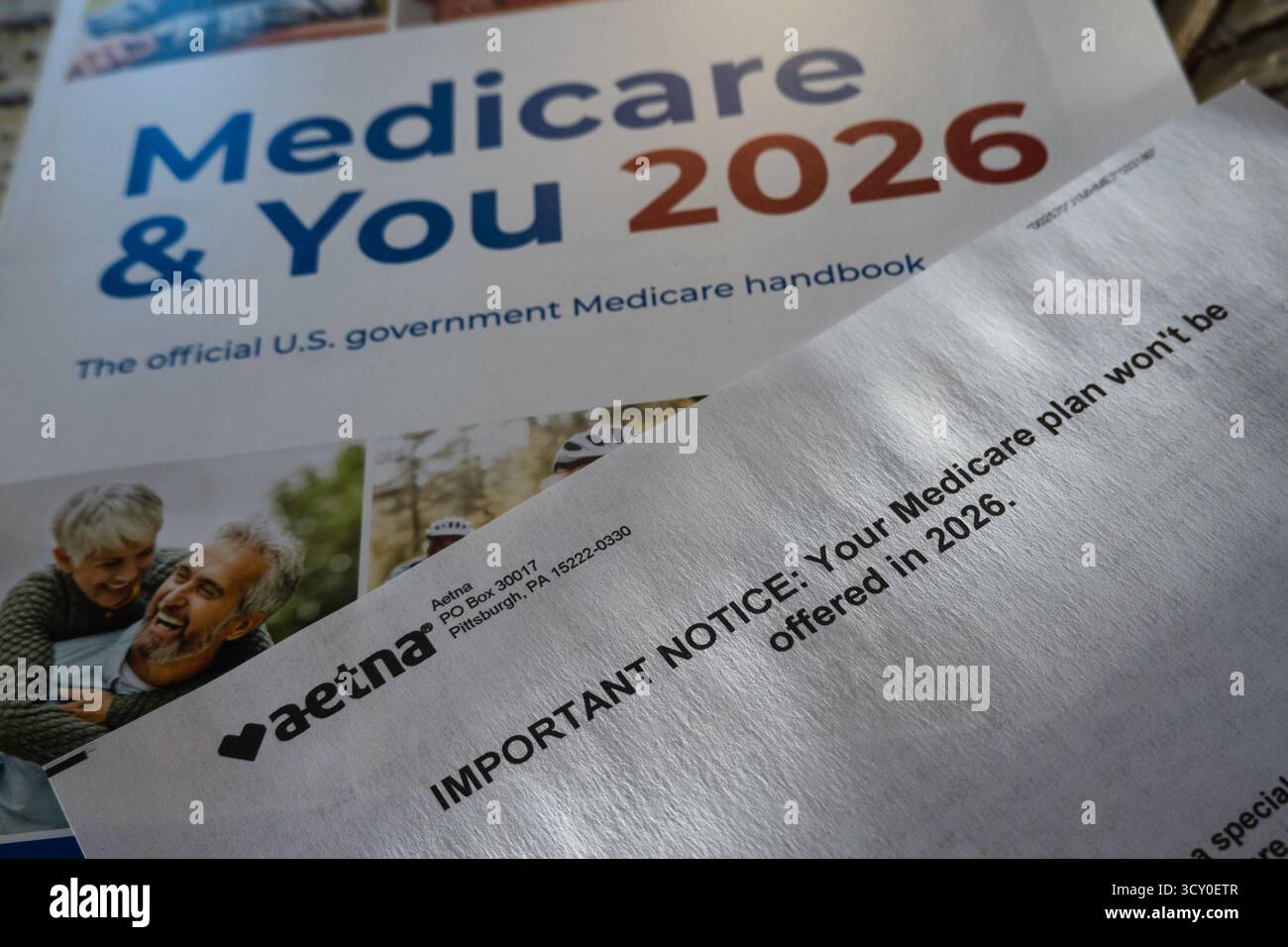Stillleben des offiziellen Handbuchs Medicare & You 2026 und des Planabbruchschreibens von Aetna, USA 2025 Stockfoto