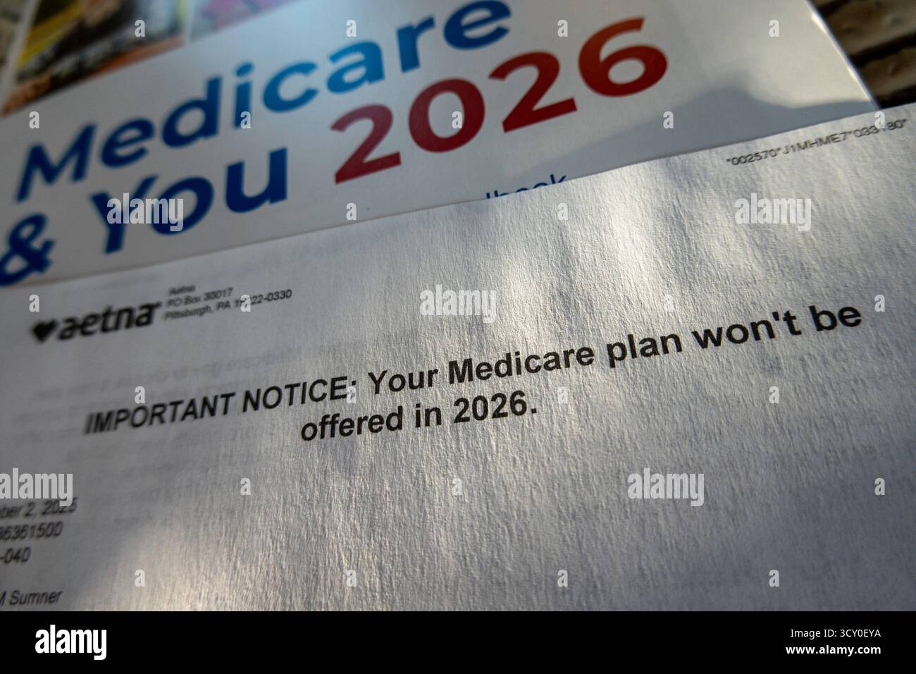 Stillleben des offiziellen Handbuchs Medicare & You 2026 und des Planabbruchschreibens von Aetna, USA 2025 Stockfoto