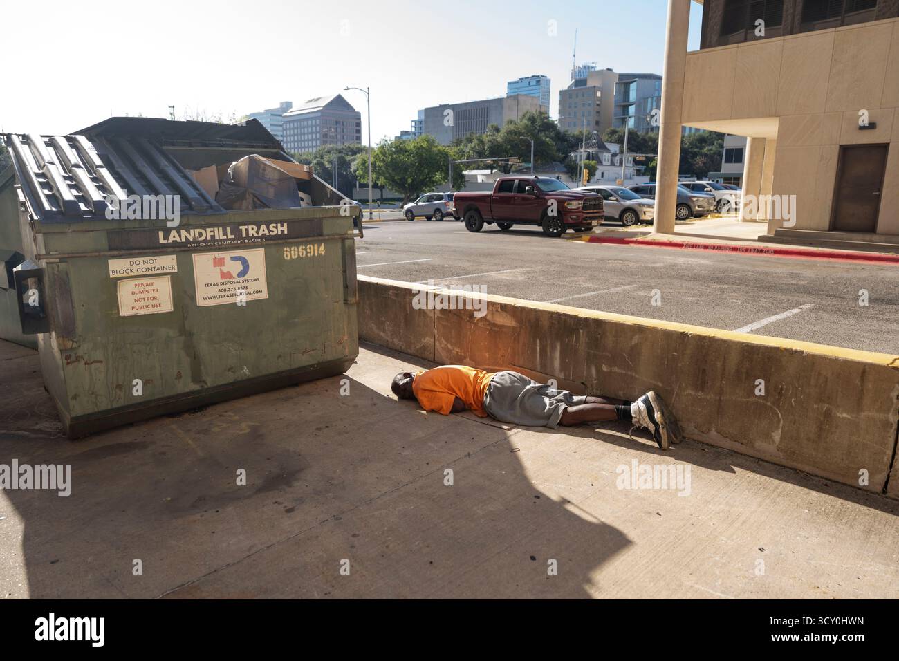 Ein Obdachloser scheint am 11. Oktober 2025 in einer Gasse in der Nähe des Texas Governor's Mansion im Hintergrund zu schlafen. Die Führer Austin versuchen weiterhin, neue Lösungen für die Hilfe der obdachlosen Bevölkerung zu finden, die täglich Schwierigkeiten hat, Unterkunft, Nahrung und Kleidung in Austin's urbanem Zentrum zu finden. Stockfoto