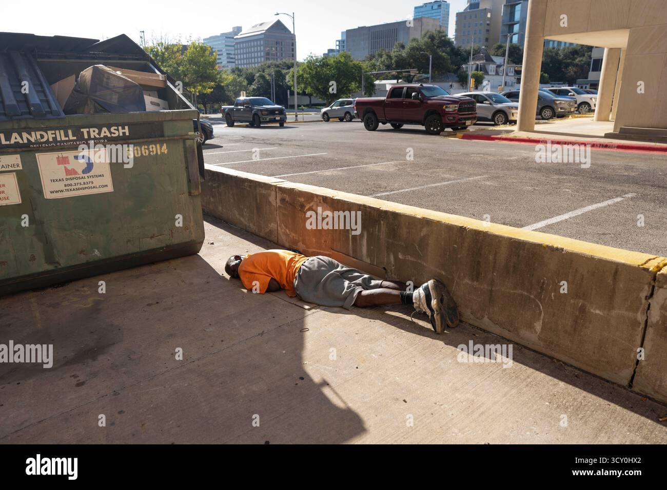 Ein Obdachloser scheint am 11. Oktober 2025 in einer Gasse in der Nähe des Texas Governor's Mansion im Hintergrund zu schlafen. Die Führer Austin versuchen weiterhin, neue Lösungen für die Hilfe der obdachlosen Bevölkerung zu finden, die täglich Schwierigkeiten hat, Unterkunft, Nahrung und Kleidung in Austin's urbanem Zentrum zu finden. Stockfoto