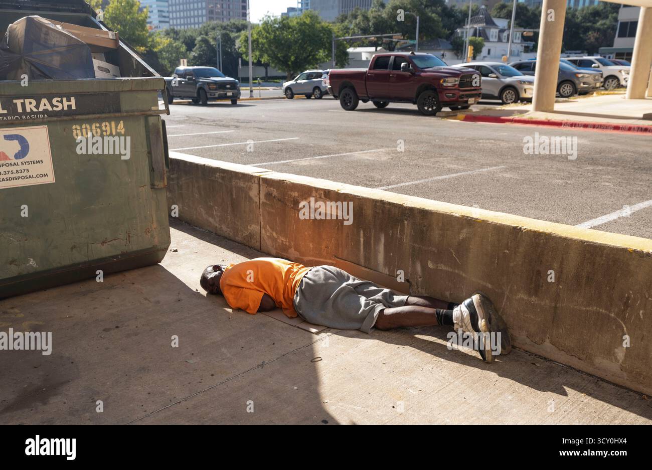 Ein Obdachloser scheint am 11. Oktober 2025 in einer Gasse in der Nähe des Texas Governor's Mansion im Hintergrund zu schlafen. Die Führer Austin versuchen weiterhin, neue Lösungen für die Hilfe der obdachlosen Bevölkerung zu finden, die täglich Schwierigkeiten hat, Unterkunft, Nahrung und Kleidung in Austin's urbanem Zentrum zu finden. Stockfoto