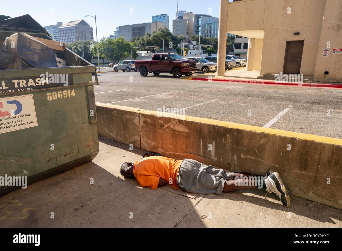 Ein Obdachloser scheint am 11. Oktober 2025 in einer Gasse in der Nähe des Texas Governor's Mansion im Hintergrund zu schlafen. Die Führer Austin versuchen weiterhin, neue Lösungen für die Hilfe der obdachlosen Bevölkerung zu finden, die täglich Schwierigkeiten hat, Unterkunft, Nahrung und Kleidung in Austin's urbanem Zentrum zu finden. Stockfoto