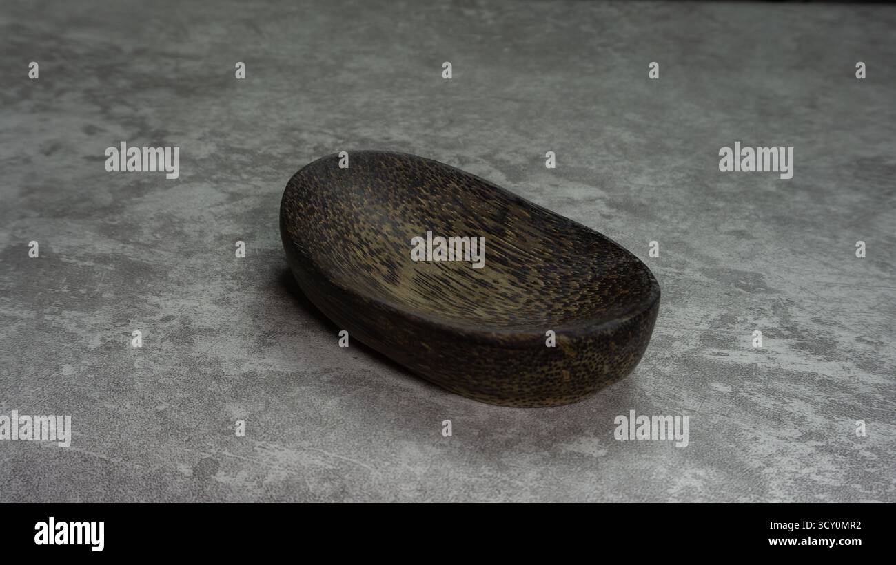 Ovale Holzplatte auf grauer Stoffoberfläche, minimales rustikales Küchengeschirr mit sauberer Zusammensetzung, natürlicher Textur und neutralem Hintergrund Stockfoto