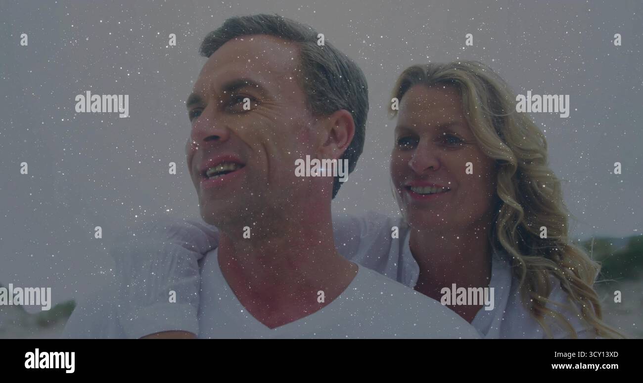 Ein Paar mittleren Alters, das weiße Hemden trägt und am Sandstrand lächelt, Filmmaske-Effekt Stockfoto