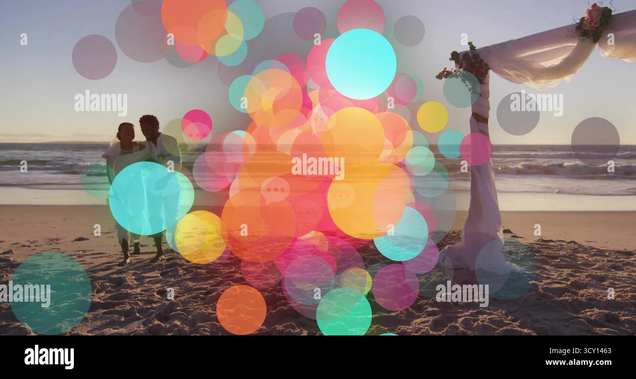 Stehende Brautpaare in Hochzeitskleidung, Blick auf den Sonnenuntergang am Strand auf den Blumenbogen, Kopierraum Stockfoto
