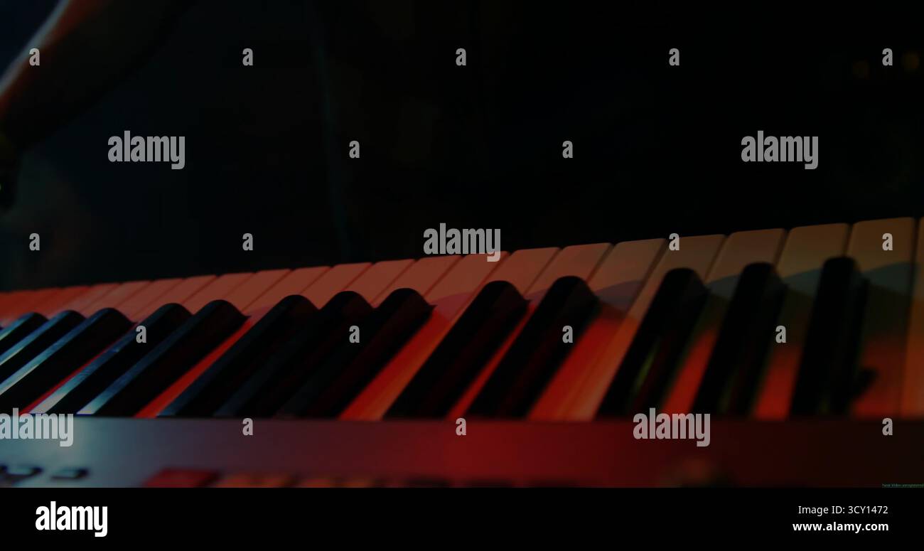 Mit elektronischer Tastatur, die farbige Bühnenleuchten im Musikstudio reflektiert, mit Tastaturständer Stockfoto