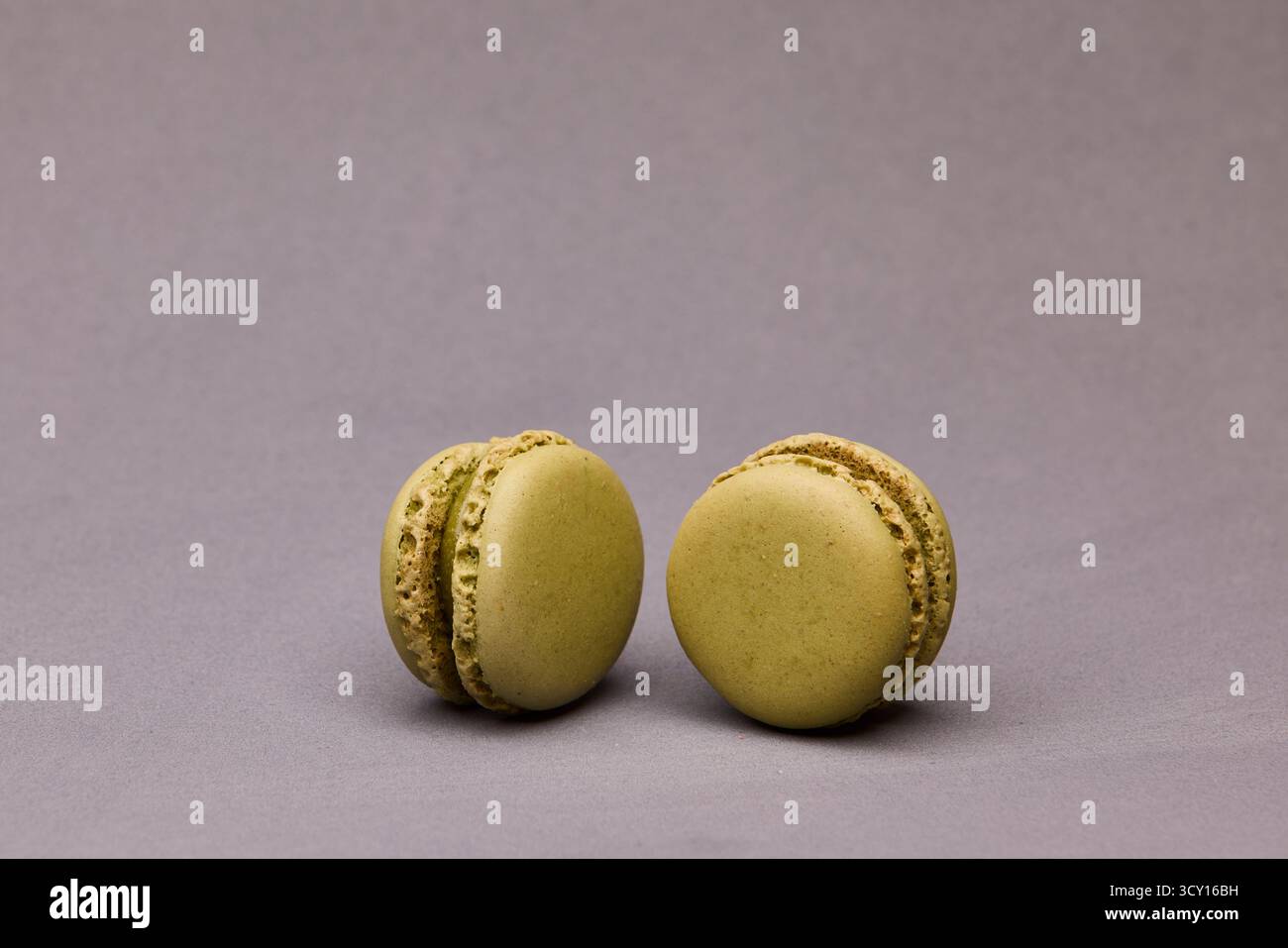 Zwei grüne und rosafarbene Macarons auf grauem Hintergrund. Einfache und farbenfrohe Dessertfotografie für Bäcker oder Design. Stockfoto