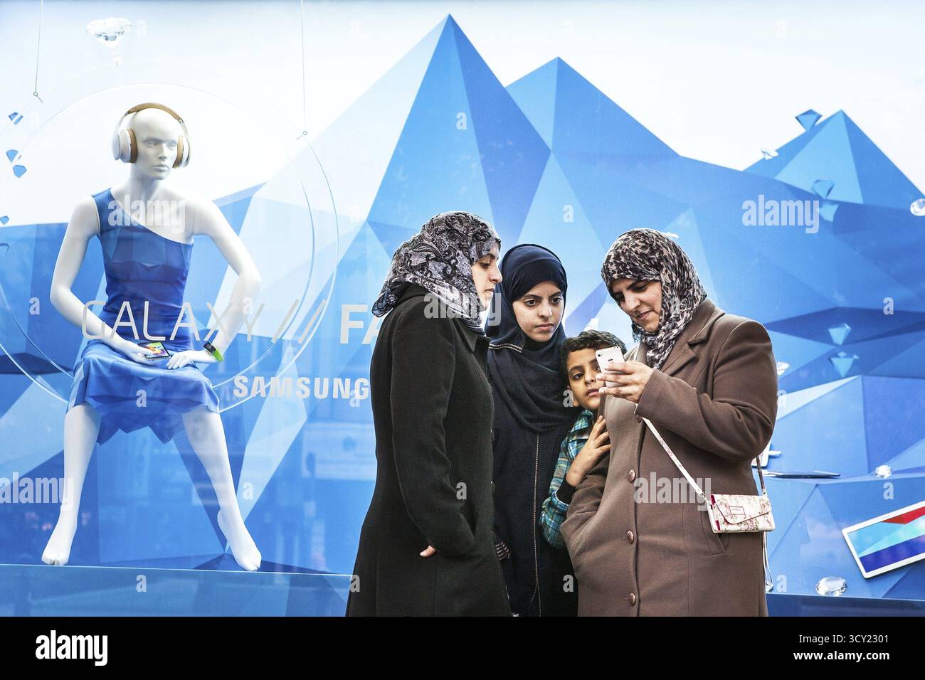 DEU Deutschland Berlin Frauen mit Kopftüchern schauen sich ein Apple iPhone an. Du stehst vor einem Schaufenster von KaDeWe, in dem Koreaner auserwählt sind Stockfoto