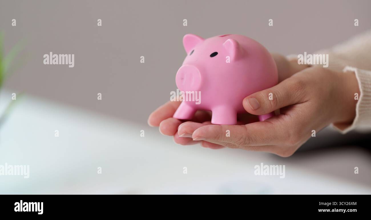 Finanzielle Einsparungen. Einzelperson, die eine Sparkasse hält, symbolisiert Sparsamkeit und finanzielle Ziele. Stockfoto