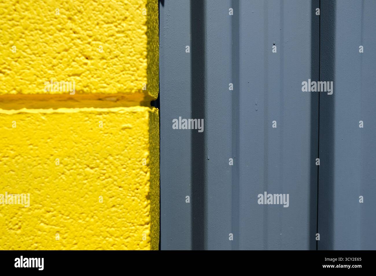 Abstraktes Foto einer gelben Ziegelmauer und einer Hangar-Türüberführung. Stockfoto
