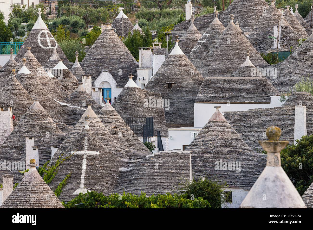 Eine wunderschöne Abendszene in Alberobello, Apulien, Italien, mit den traditionellen Trulli-Häusern, die sanft in warmem Licht leuchten. Die konischen Dächer und weiß Stockfoto Eine wunderschöne Abendszene in Alberobello, Apulien, Italien, mit den traditionellen Trulli-Häusern, die sanft in warmem Licht leuchten. Die konischen Dächer und weiß Stockfoto