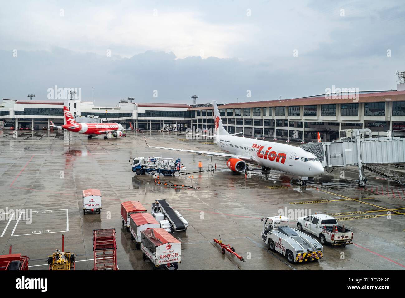 Bangkok, Thailand - 15. Oktober 2025 - Thai Lion Air bereitet sich bei regnerischem Wetter am Don Muang Airport Gate auf das Boarding vor, mit Bodenbesatzung und Fahrzeugen Stockfoto