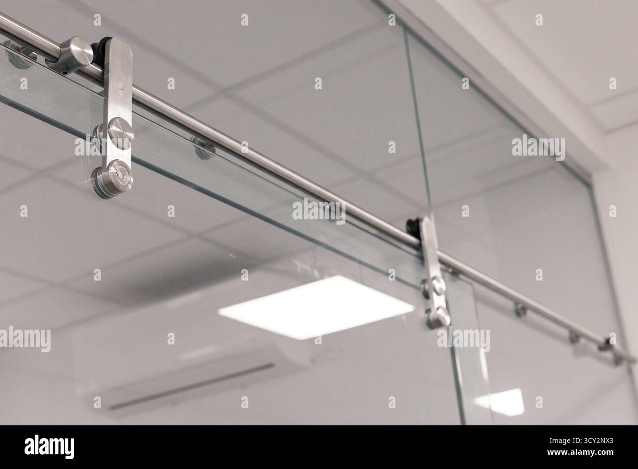 Eine Nahaufnahme der eleganten Schiebetürbeschläge mit polierten Metallkomponenten und Glasplatten. Diese Einrichtung veranschaulicht das zeitgenössische Design in einem Stockfoto