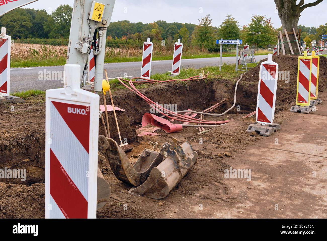 Roden, Niederlande; 8. Oktober 2025: Aushubgraben für neues 10-kV-Stromnetz mit sichtbaren roten Aluminium-Dreiphasenkabeln und Teilen Mini e Stockfoto