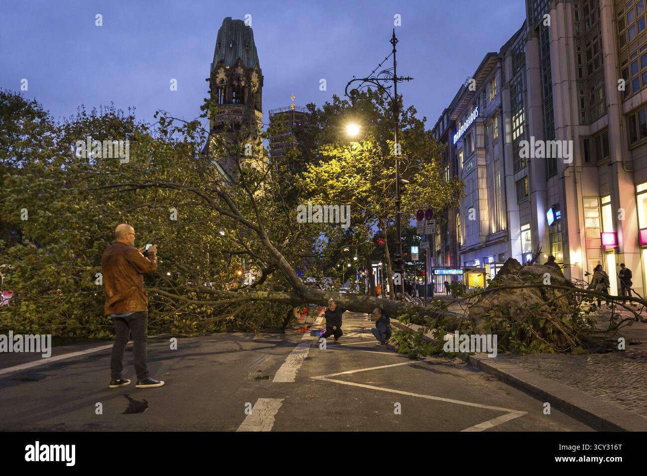 DEU Deutschland Berlin Feuerwehreinsatz am Kurfürstendamm. Sturm Xavier hatte Bäume auf die Straße fallen lassen. Vater nimmt ein Souvenir Stockfoto