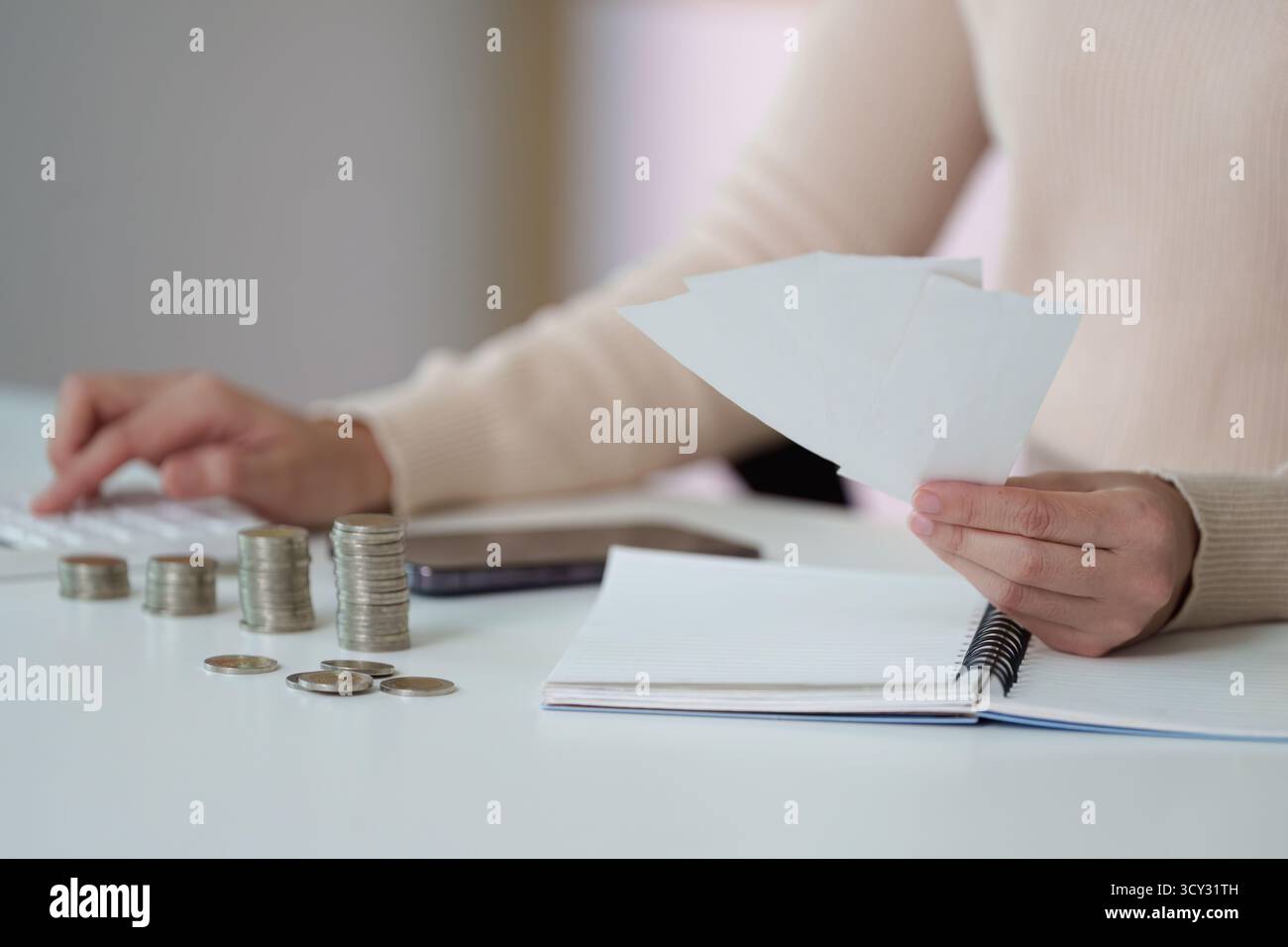 Finanzplanung. Person, die Finanzen mit Münzen und Dokumenten an einem Schreibtisch organisiert. Stockfoto