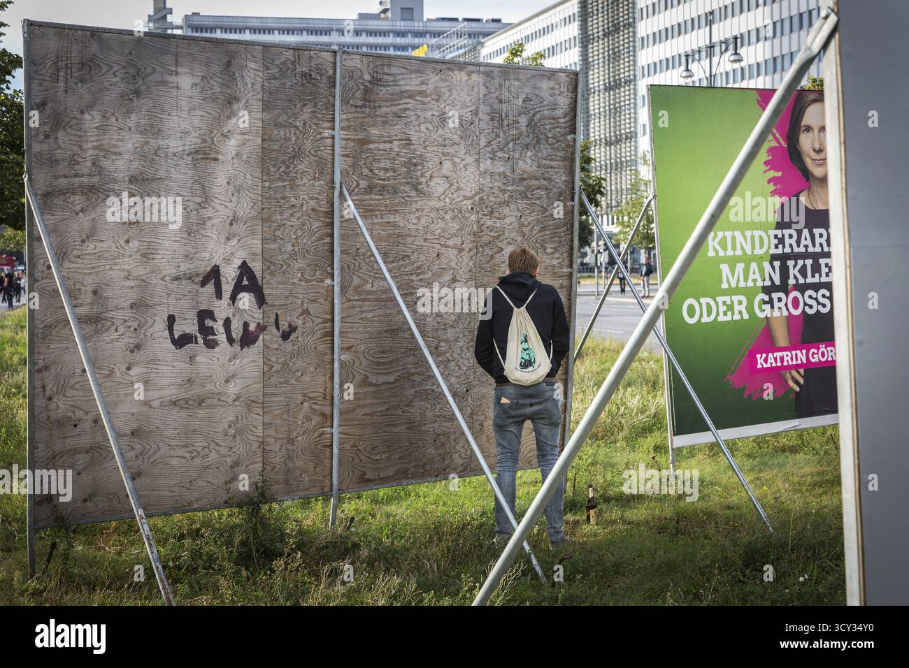 DEU Deutschland Berlin Demonstration „Wer gehört die Stadt“ von Musikfans und Clubbesuchern durch Berlin-Mitte. Ein Mann pinkelt hinter ein Wahlplakat Stockfoto