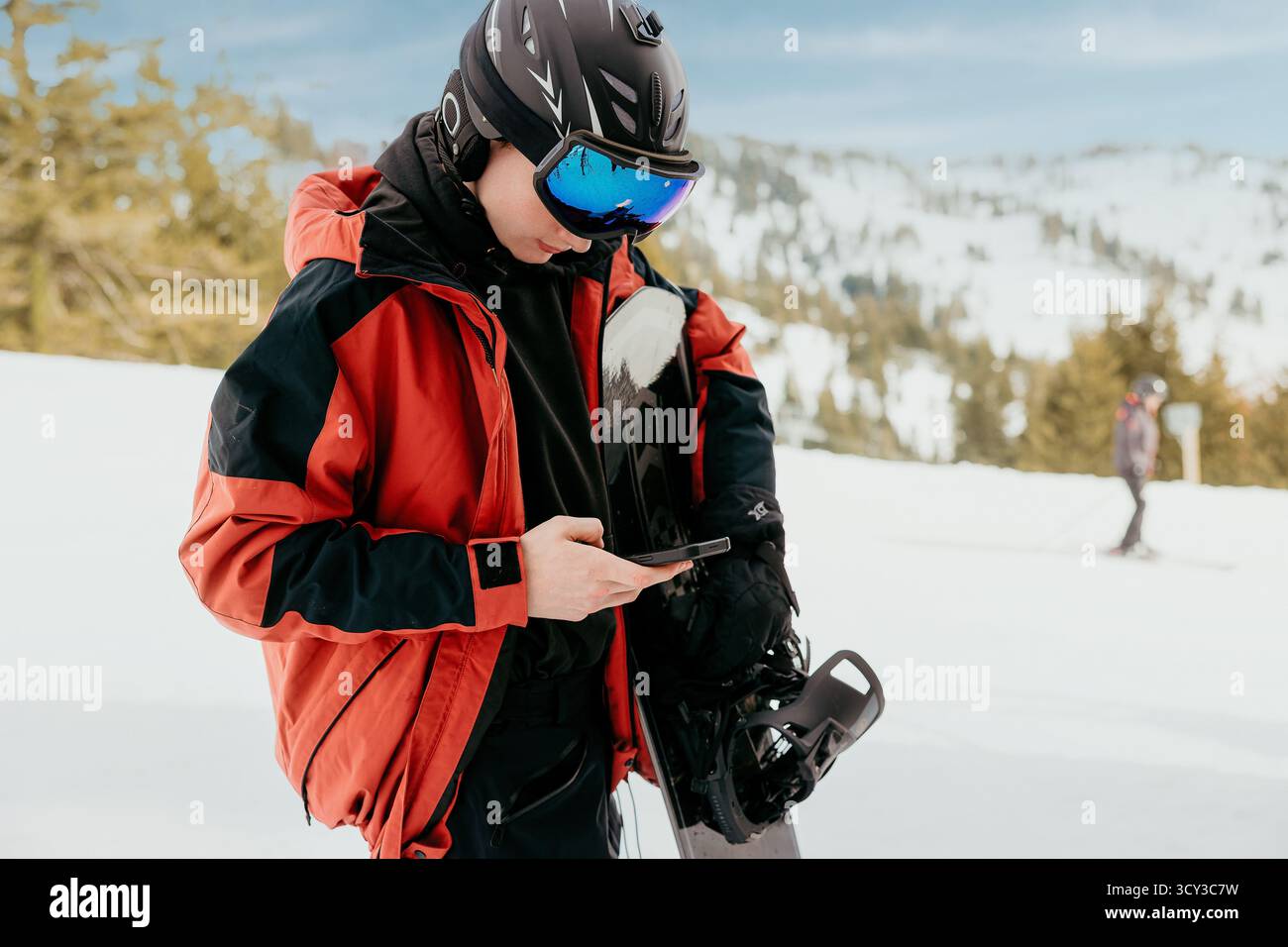 Snowboarder checken Telefon im Skigebiet Stockfoto