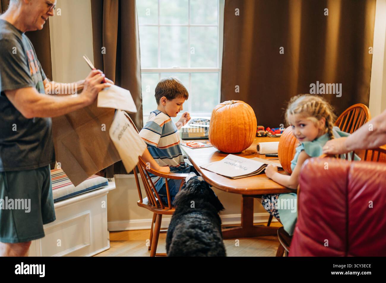 Die Familie bereitet sich auf Kürbisschnitzereien am Küchentisch mit Kindern vor Stockfoto