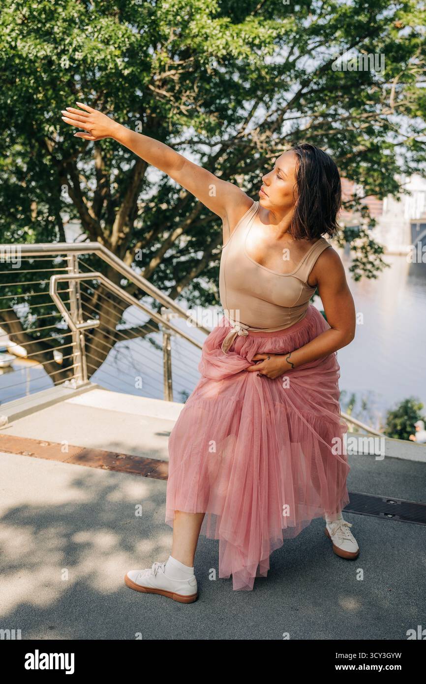 Tänzerin posiert mit ausgestreckten Armen in urbaner Umgebung Stockfoto