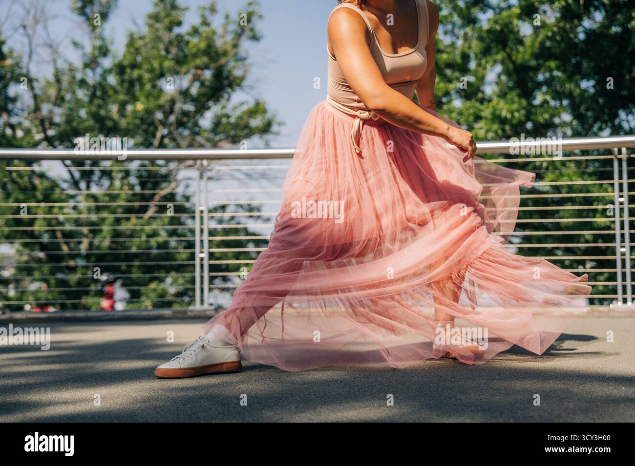 Frau tanzt draußen in rosa Tüllrock an sonnigen Tagen Stockfoto
