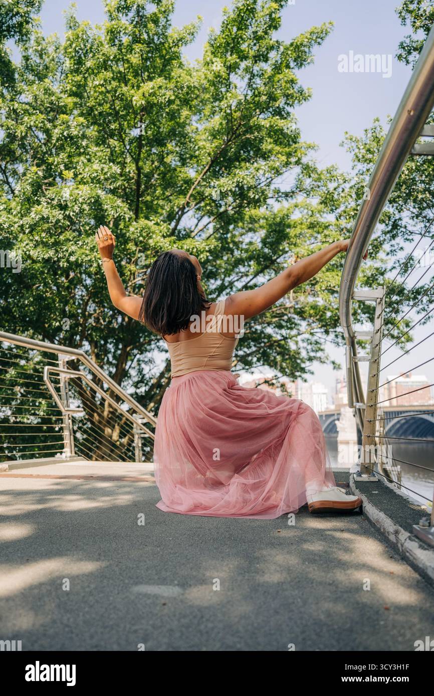 Frau tanzt Freiheit und Freude draußen auf der Brücke Stockfoto