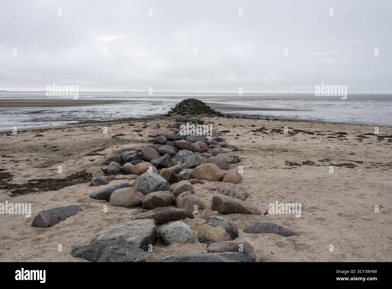 Vom Sandstrand auf der Insel Foehr erstreckt sich eine Steingroyne aus großen Granitblöcken bis weit ins Wattenmeer in Schleswig-Holstein Stockfoto