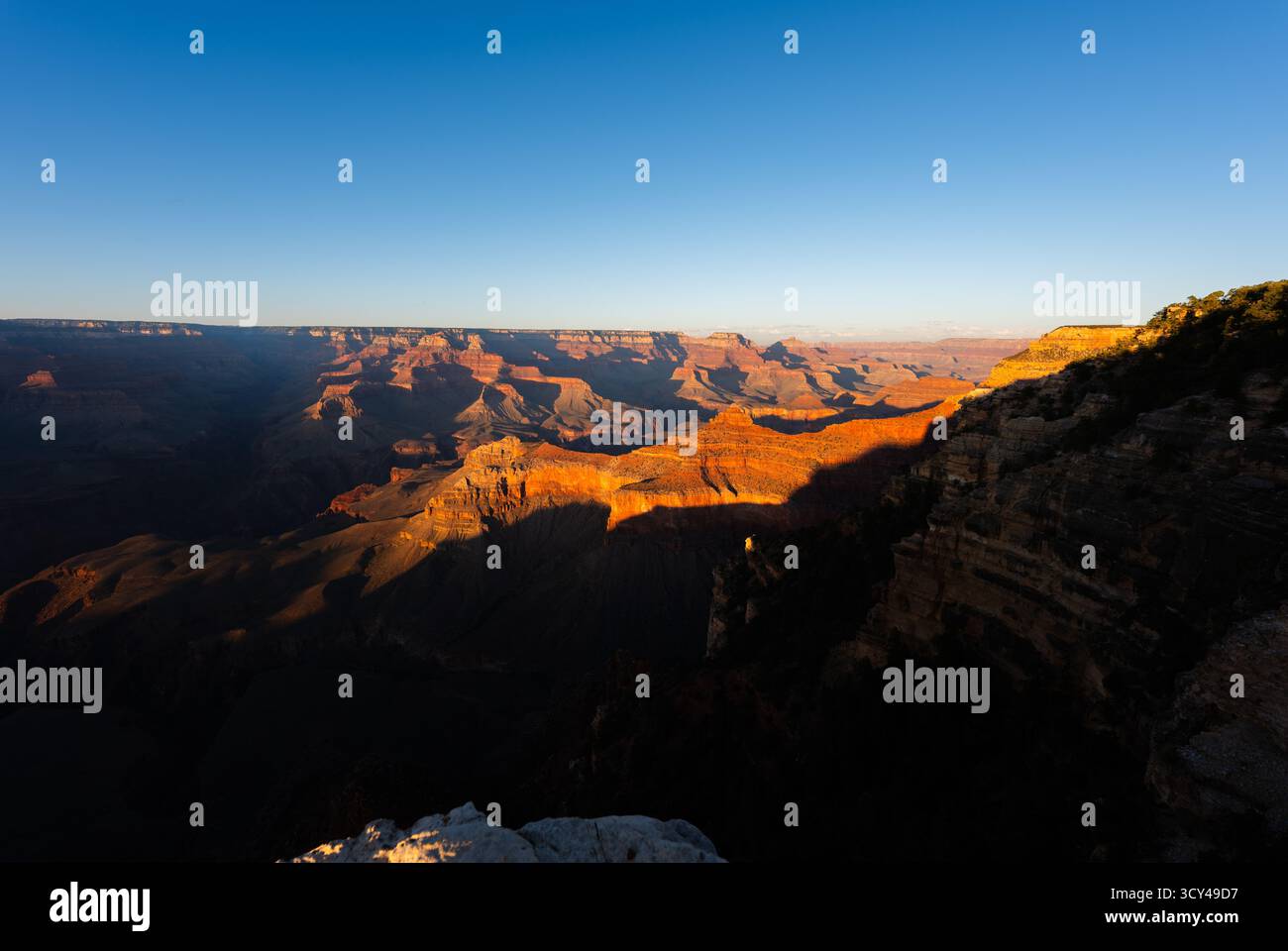 Lange Schatten und verblassendes Abendlicht ziehen sich über den Grand Canyon und heben dramatische Klippen, Sandstein und die landschaftliche Schönheit hervor Stockfoto