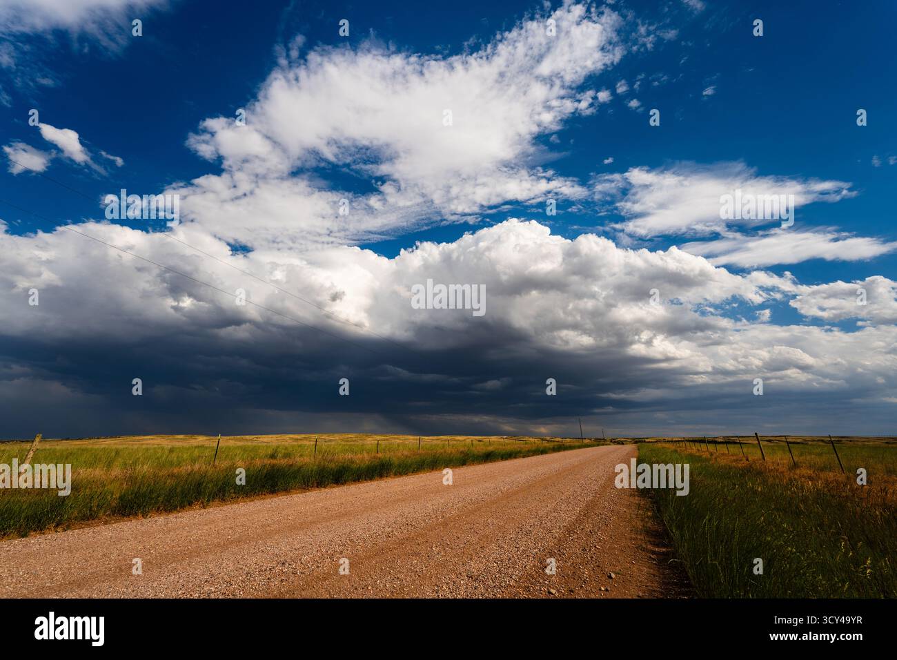 Flauschige Wolken bewegen sich langsam über eine ruhige Schotterstraße und schaffen einen friedlichen, stimmungsvollen Himmel mit sanfter Textur und sanften Bewegungen, der die subtile Schönheit einfängt Stockfoto